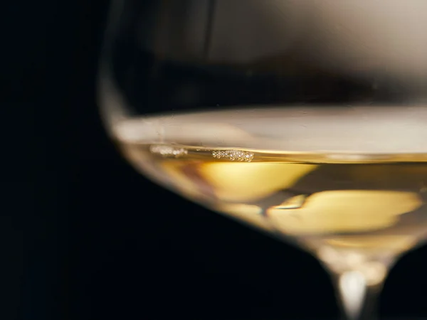 Primo piano di un calice di vino bianco su sfondo scuro