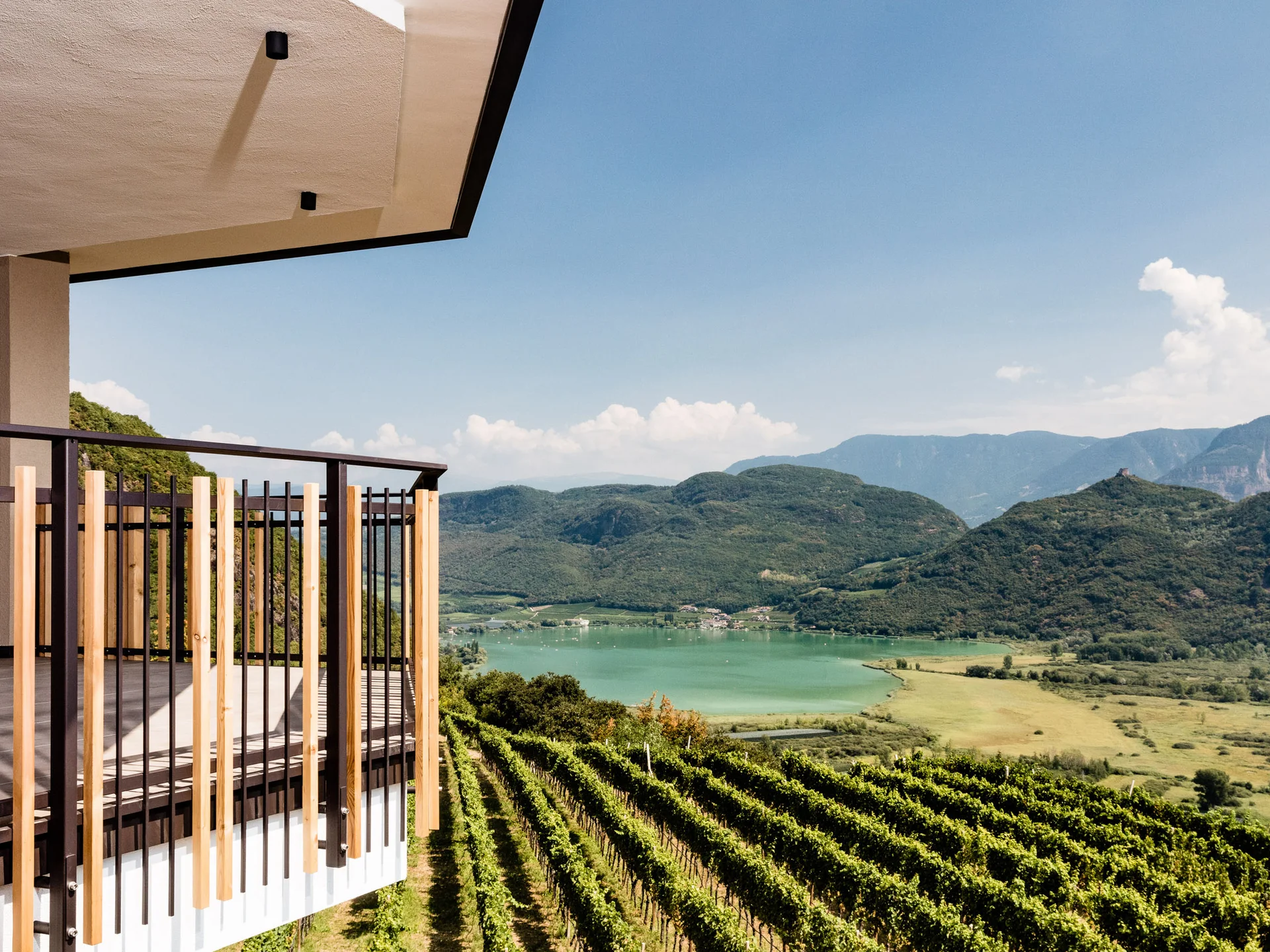 Balkon mit Blick auf Weinberg, See und Berge unter blauem Himmel