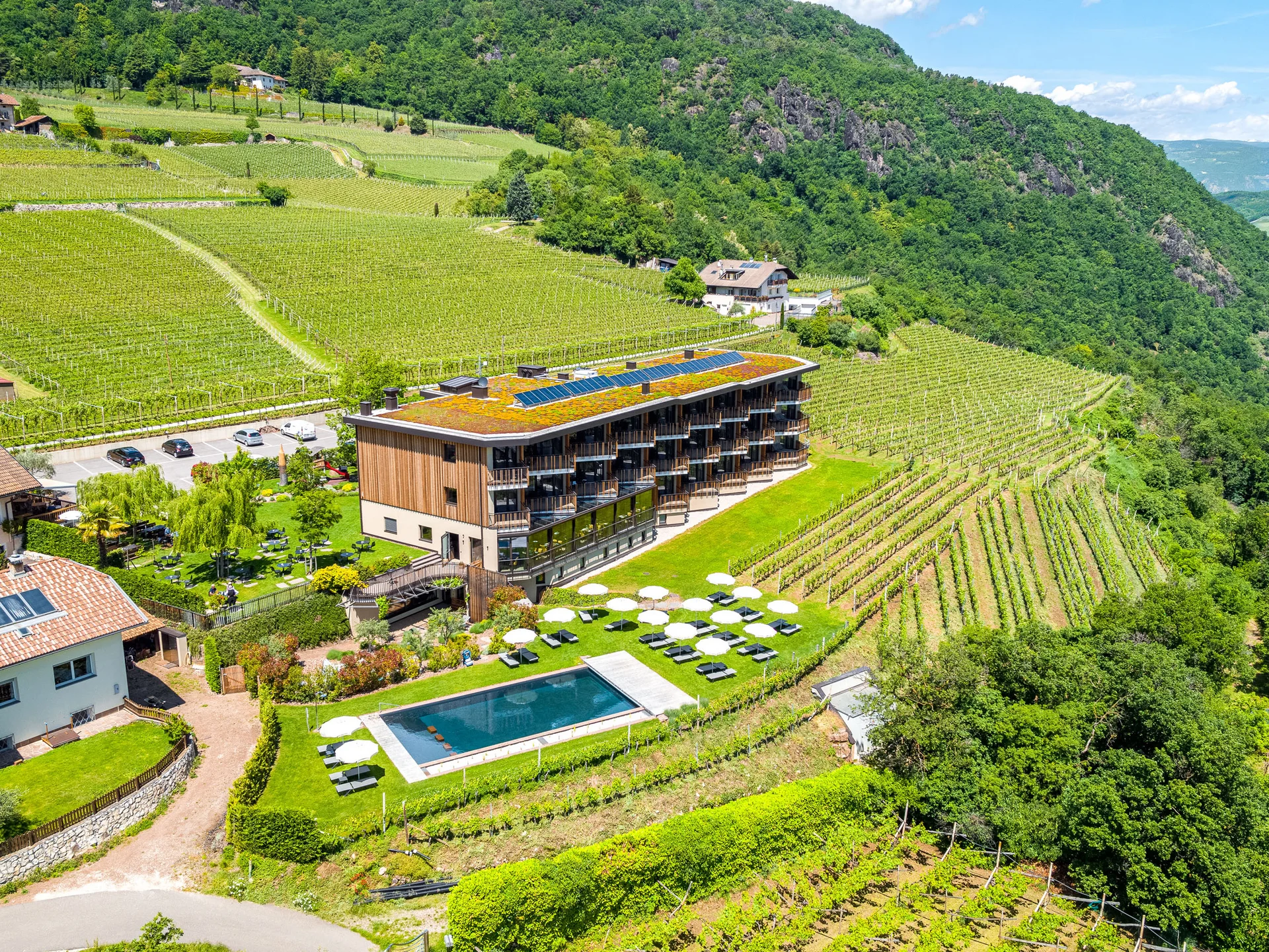Hotel mit Pool und Sonnenschirmen inmitten von Weinbergen und Bergen