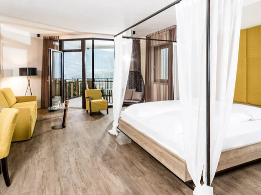Hotel Plattenhof: your home amongst the vineyards Modern hotel room with canopy bed, yellow furniture and balcony with mountain view