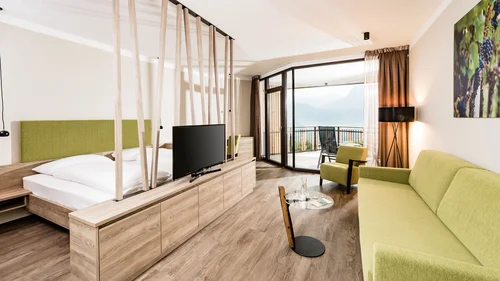 Offerte per la vostra vacanza all'Hotel Plattenhof di Termeno Moderna camera d'albergo con divano verde, letto e balcone con vista sulle montagne
