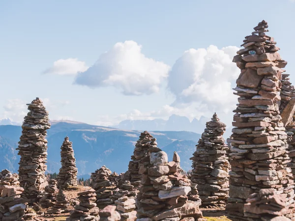 Places of interest in Tramin and the surrounding area Several tall piles of stones in front of a mountain landscape and a blue sky with clouds.