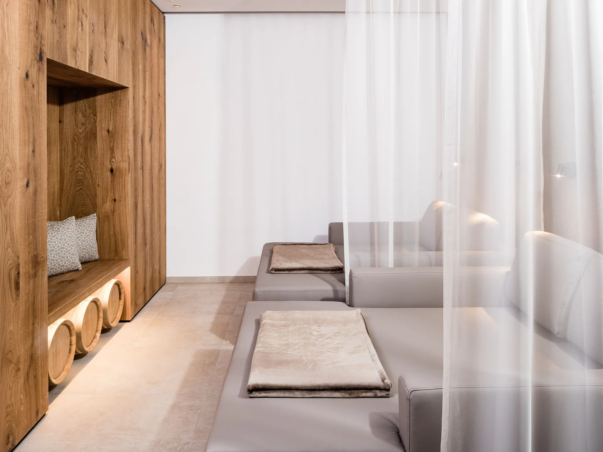 Modern relaxation room with grey loungers and wooden wall with seating alcove