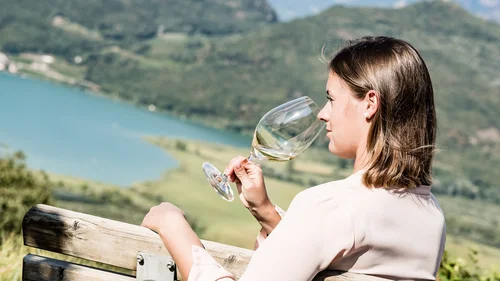 Offerte per la vostra vacanza all'Hotel Plattenhof di Termeno Donna che si gode un bicchiere di vino bianco con vista sul lago e sulle montagne
