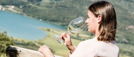 Donna che si gode un bicchiere di vino bianco con vista sul lago e sulle montagne