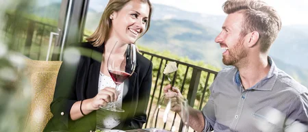Couple enjoying wine and food on terrace with mountain view