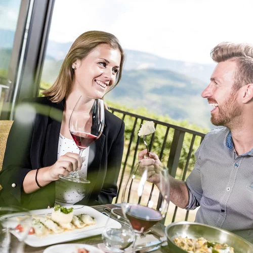 Couple enjoying wine and food on terrace with mountain view