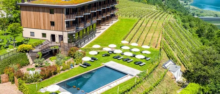 Hotel con piscina e ombrelloni tra i vigneti in un paesaggio collinare