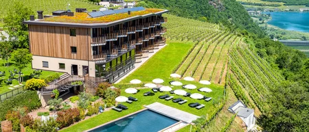 Hotel with pool and sun umbrellas among vineyards in a hilly landscape