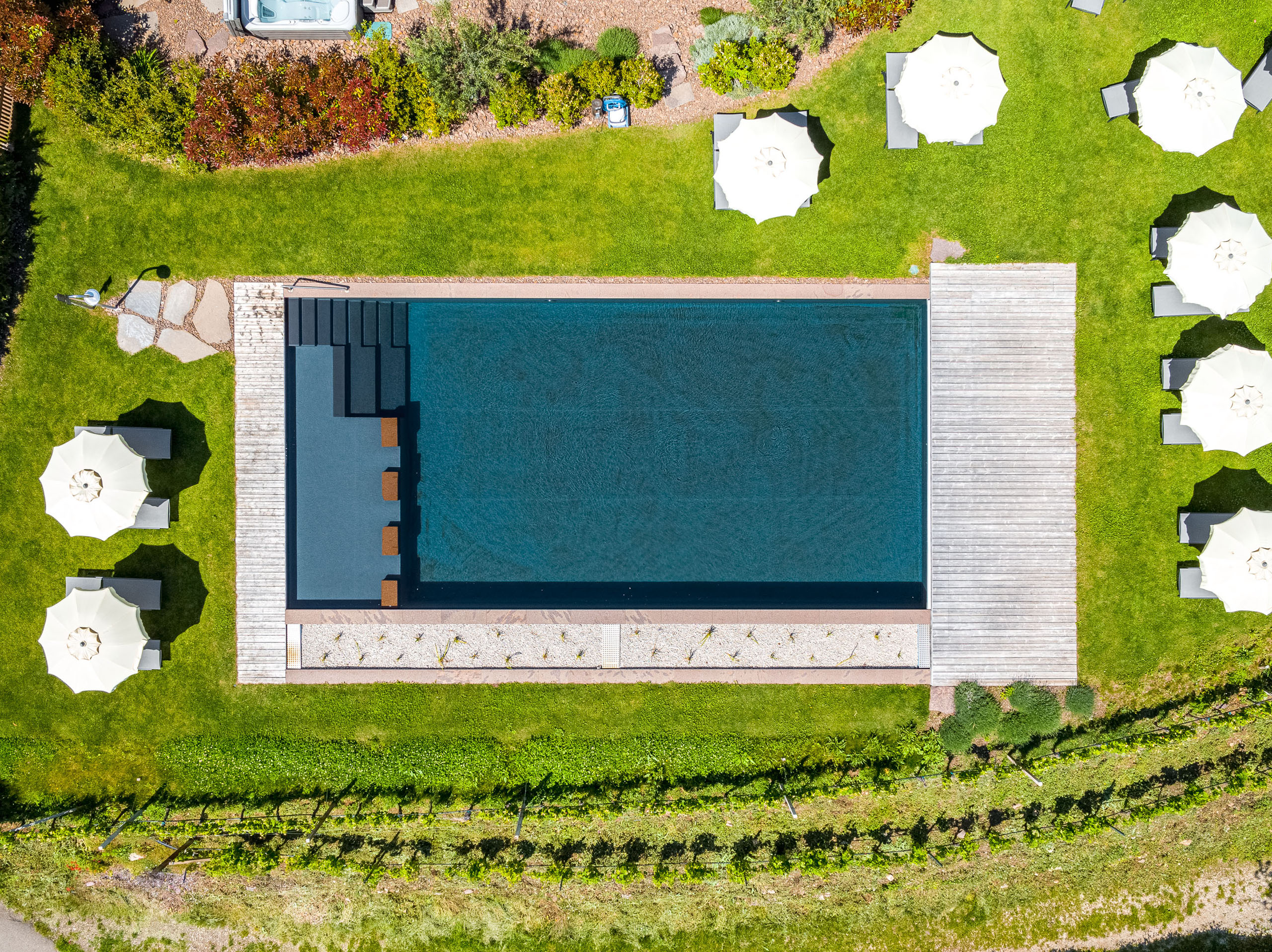 Bildergalerie: Eindrücke aus dem Plattenhof in Tramin Vogelperspektive eines rechteckigen Pools mit Sonnenschirmen und Liegestühlen im Garten