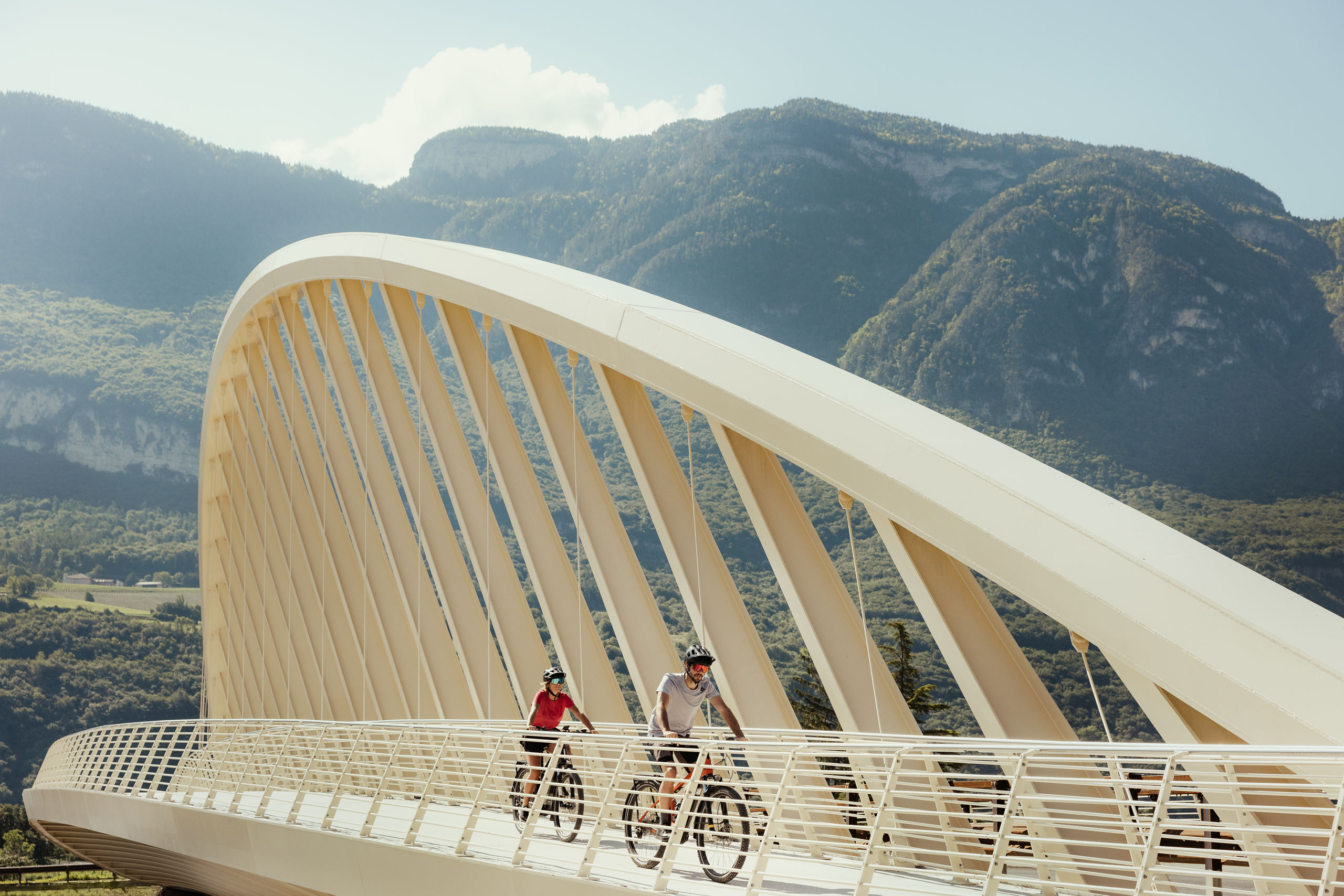 Bildergalerie: Eindrücke aus dem Plattenhof in Tramin Zwei Radfahrer auf moderner Brücke vor Berglandschaft